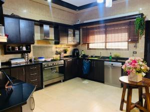 a large kitchen with wooden cabinets and a table with flowers at Laura’s Modern Villa in Madaba