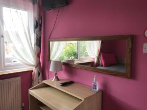 um quarto com um espelho numa parede cor-de-rosa em Becontreelodge em Dagenham