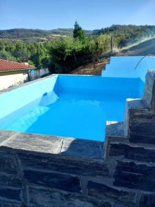 a large swimming pool with blue water and stairs at Alojamento Local Madre de Cima in Vinhais