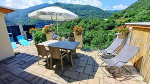 a patio with a table and chairs and an umbrella at vallemaira house CASA BELVEDERE LUCE & SOLE 10 POSTI LETTO in San Damiano Macra