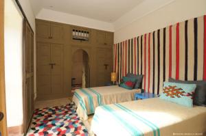 een slaapkamer met 2 bedden en een gestreepte muur bij Dar al Hossoun in Taroudant
