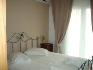 a bedroom with a bed with white sheets and a window at Merlot Village Rental Apartments in Kariá