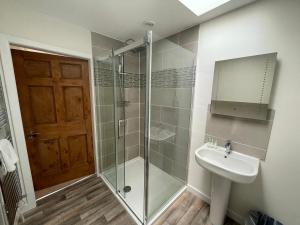 a bathroom with a glass shower and a sink at Holiday House at 22, Contemporary 3 bedroom cottage in historic Wigtown in Wigtown