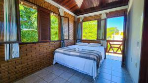 1 dormitorio con 1 cama en una habitación de ladrillo con ventanas en Pousada Encantos da Natureza, en Praia do Frances