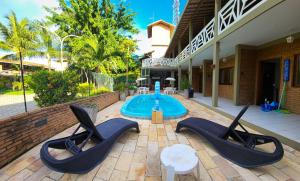 a patio with two chairs and a swimming pool at Pousada Encantos da Natureza in Praia do Frances