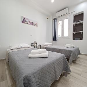 two beds in a white room with towels on them at Zoggos Apartment in Áyios Pétros