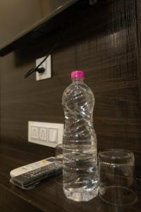 Hotel Siddharth A Boutique Guest House في نيودلهي: وجود زجاجة مياه على طاولة مع جهاز تحكم عن بعد