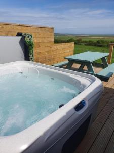 a hot tub on a deck with a picnic table at Lilly's Lodges Orkney Robin Lodge in Orkney