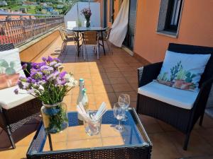 a table with flowers and wine glasses on a balcony at Apartamento en el centro de Cedeira nuevo y con terraza in Cedeira