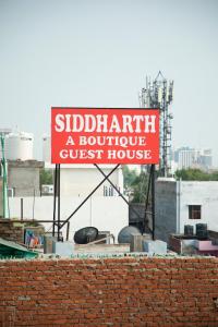 un panneau indiquant une maison d'hôtes sur le toit sur un mur de briques dans l'établissement Hotel Siddharth A Boutique Guest House, à New Delhi