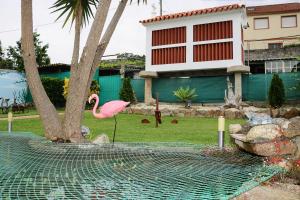 a flamingo is standing in a fence in a yard at Descanso Natural Bueu in Bueu