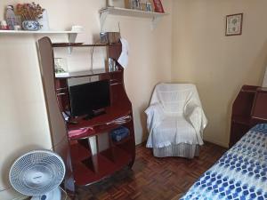 a room with a television and a chair in a room at Quarto no Centro de Juiz de Fora in Juiz de Fora