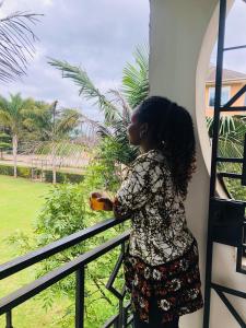 a woman standing on a balcony looking out the window at KAMAO Hotel in Arusha