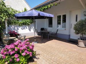 eine Terrasse mit einem blauen Regenschirm und rosa Blumen in der Unterkunft Ferienwohnung Kirschblüte in Billigheim-Ingenheim
