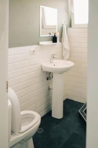 a white bathroom with a sink and a toilet at Patio Rooms Gjirokaster in Gjirokastër +45 photos