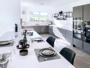 una cocina blanca con una mesa larga con sillas negras en The View Suite, en Brücktal