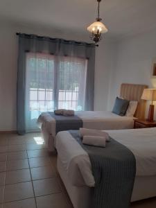 sypialnia z 3 łóżkami i oknem w obiekcie Casa da Praia - Golf Resort Praia D'El Rey w mieście Amoreira