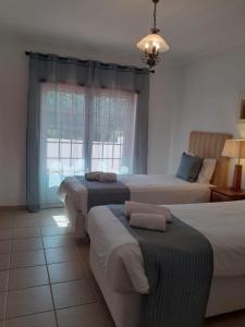 a bedroom with three beds and a window at Casa da Praia - Golf Resort Praia D'El Rey in Amoreira