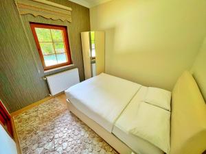 een kleine slaapkamer met een wit bed en een raam bij Raha Villa Bungalow in Uzungol