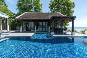 a swimming pool in front of a house with a gazebo at Beach Front Villa in Ban Bang Po