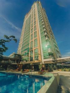 a tall building with a pool in front of it at Ayala Mall 10mins walk Cebu City Apartment & Pool in Cebu City