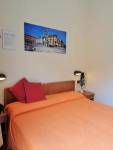 ein Schlafzimmer mit einem Bett mit orangefarbener Bettwäsche und einem Bild an der Wand in der Unterkunft Hotel Lariana in Rimini