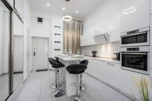 a white kitchen with two bar stools and a counter at Opera Luxury Apartment in Budapest