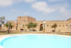 una gran piscina frente a un edificio de ladrillo en Masseria Galatea Agriturismo, en Alessano