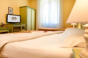 a bedroom with a large white bed with a television at Hotel Minerva in Assisi