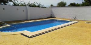 a swimming pool in a yard with a white wall at Alojamiento rural " Las Carmenes " in Algar