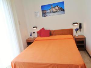 ein Schlafzimmer mit einem Bett mit einer orangefarbenen Tagesdecke in der Unterkunft Hotel Lariana in Rimini