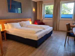 ein Hotelzimmer mit einem Bett und zwei Fenstern in der Unterkunft Hotel Aquamarin in Papenburg