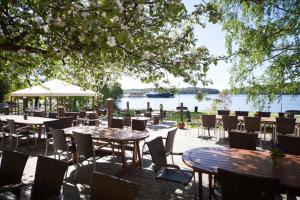 a patio with tables and chairs and a view of the water at Hotel Hospitz in Savonlinna