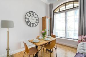 uma sala de jantar com uma mesa e um relógio na parede em Craig Leith Apartment em Alloa