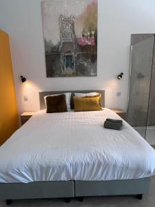 a bedroom with a white bed with a painting on the wall at Whaaw Herentals in Herentals