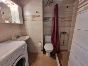 a bathroom with a toilet a sink and a washing machine at tripoli central accommodation in Tripolis