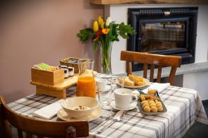 een tafel met ontbijtproducten en een vaas met bloemen bij döit - Turismo e Cultura in Conialo