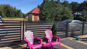 two pink chairs sitting next to a fence at pokoje goscinne Damian in Mrzeżyno