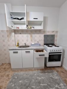 a white kitchen with a sink and a stove at Birchwood place in Sarajevo