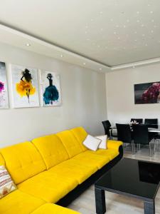 um sofá amarelo numa sala de estar com uma mesa em Best City Apartment em Hanôver