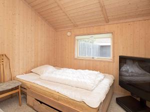 a bed in a wooden room with a television at Holiday home Slagelse XX in Slagelse