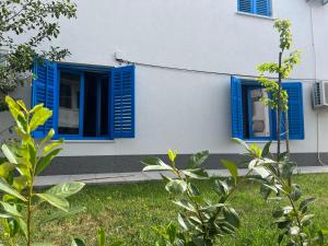 a house with blue shutters and a yard at Doneto, apartment in private house in Rijeka