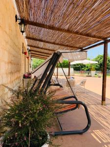 a bench under a wooden roof with an umbrella at Il Casale di Luisa in Modica