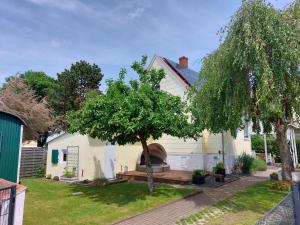 een wit huis met een boom in de tuin bij Haus Liebevoll in Wald 102 in Gunzenhausen