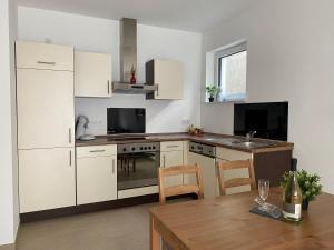 a kitchen with white cabinets and a table with a bottle of wine at Ferienwohnung Im Dhrontal in Gräfendhron