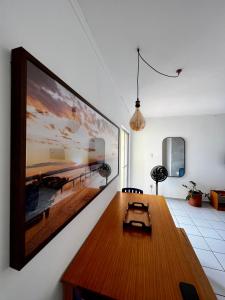 ein Wohnzimmer mit einem Holztisch und einem Bild an der Wand in der Unterkunft Vale Hospedar Califórnia Apart in Petrolina