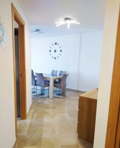 a dining room with a table and chairs and a clock on the wall at Apartamento en sol, Ador in Ador