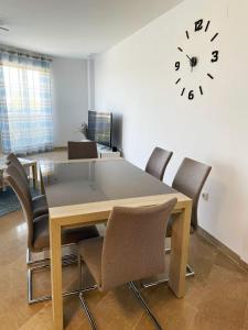 a dining room table with chairs and a clock on the wall at Apartamento en sol, Ador in Ador