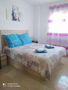 a bedroom with a bed with blue pillows at Apartamento en sol, Ador in Ador