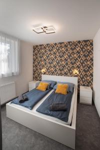 1 dormitorio con 1 cama grande con sábanas azules y almohadas amarillas en Melitta Vendégház en Magyarhertelend